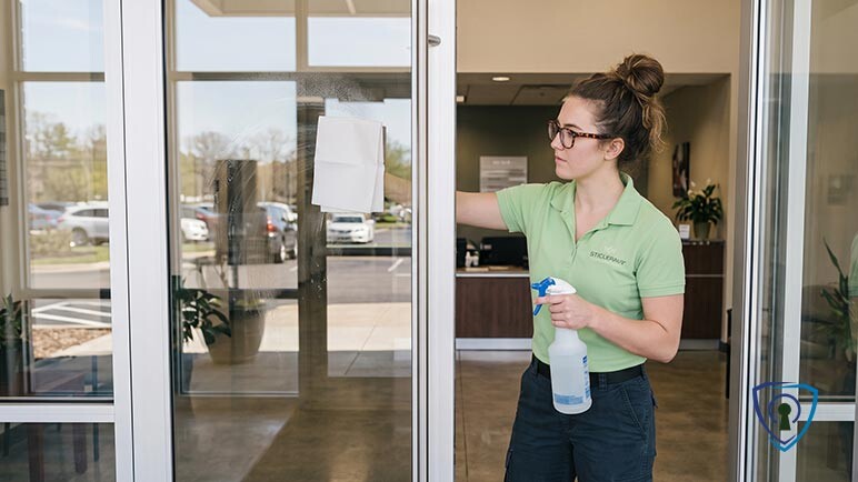 day porter cleans window glass at office building.